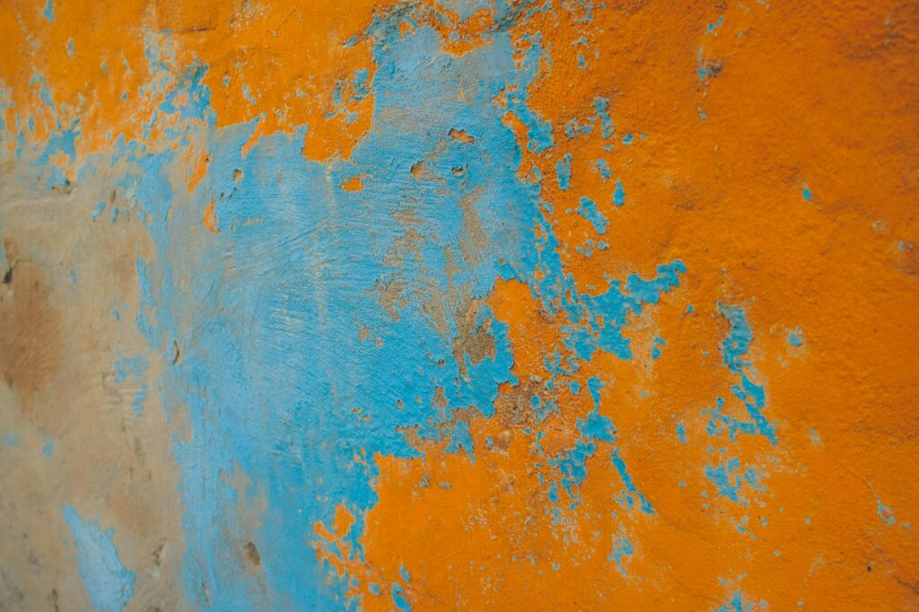 an orange and blue wall with peeling paint